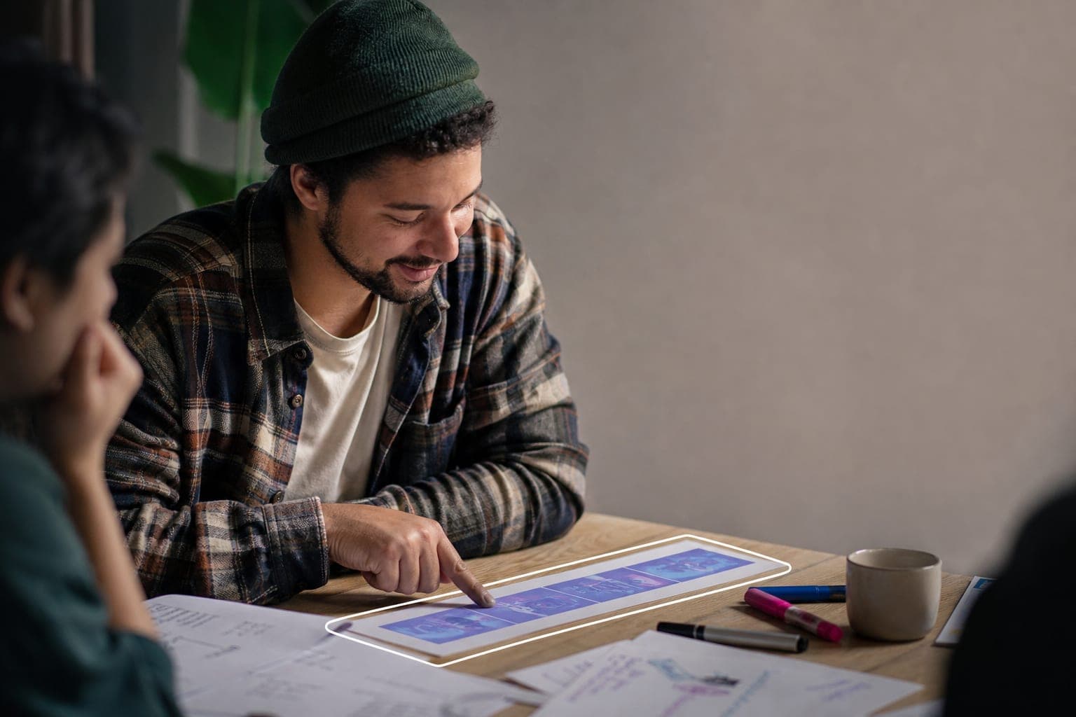 A young man in a focus group reviewing an ad storyboard on a tablet, pointing to the frame that landed for him.