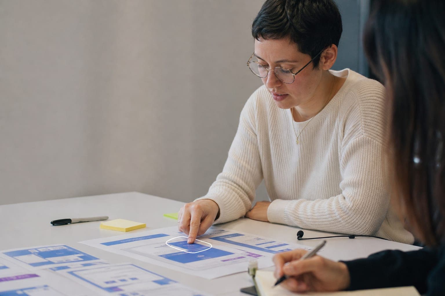 A woman in a usability session thinking aloud as she points to a paper prototype screen.